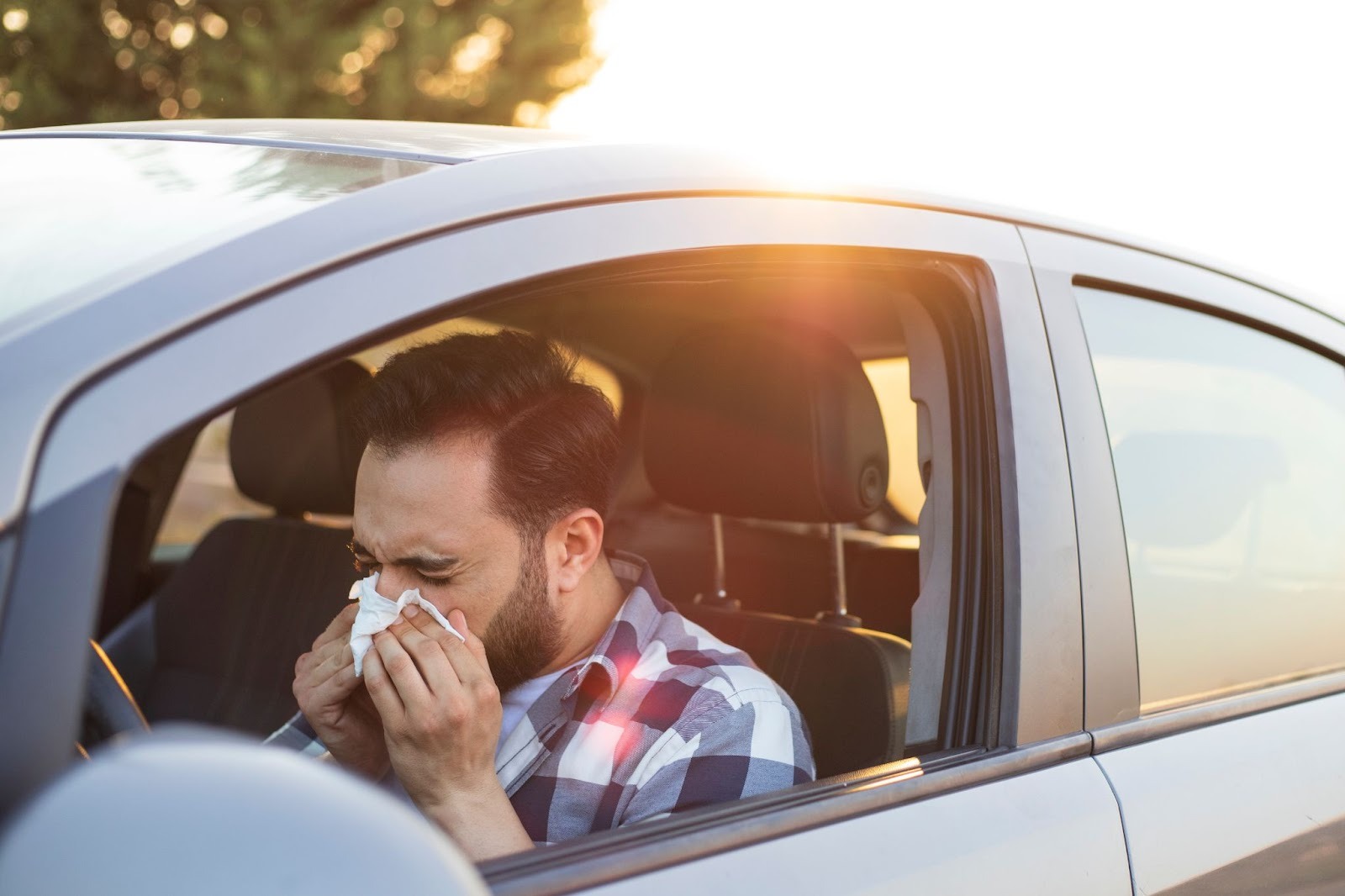 man in car blowing his nose