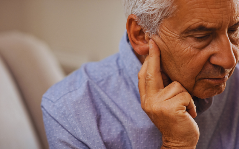 An older man holding his ear