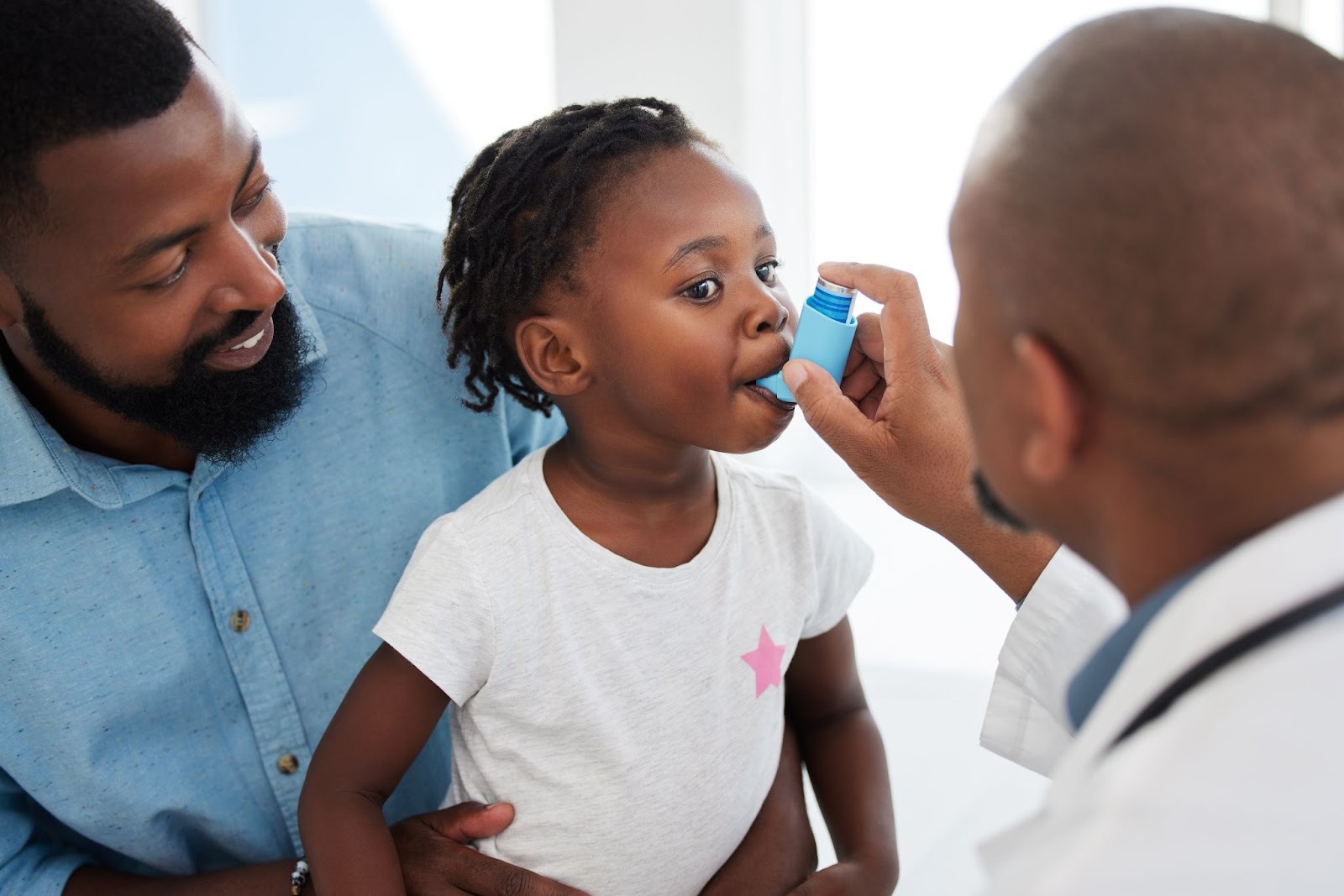 A doctor showing a little girl how to use an inhaler