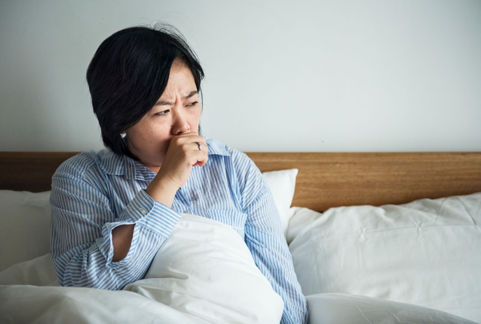 A woman sitting in bed coughing