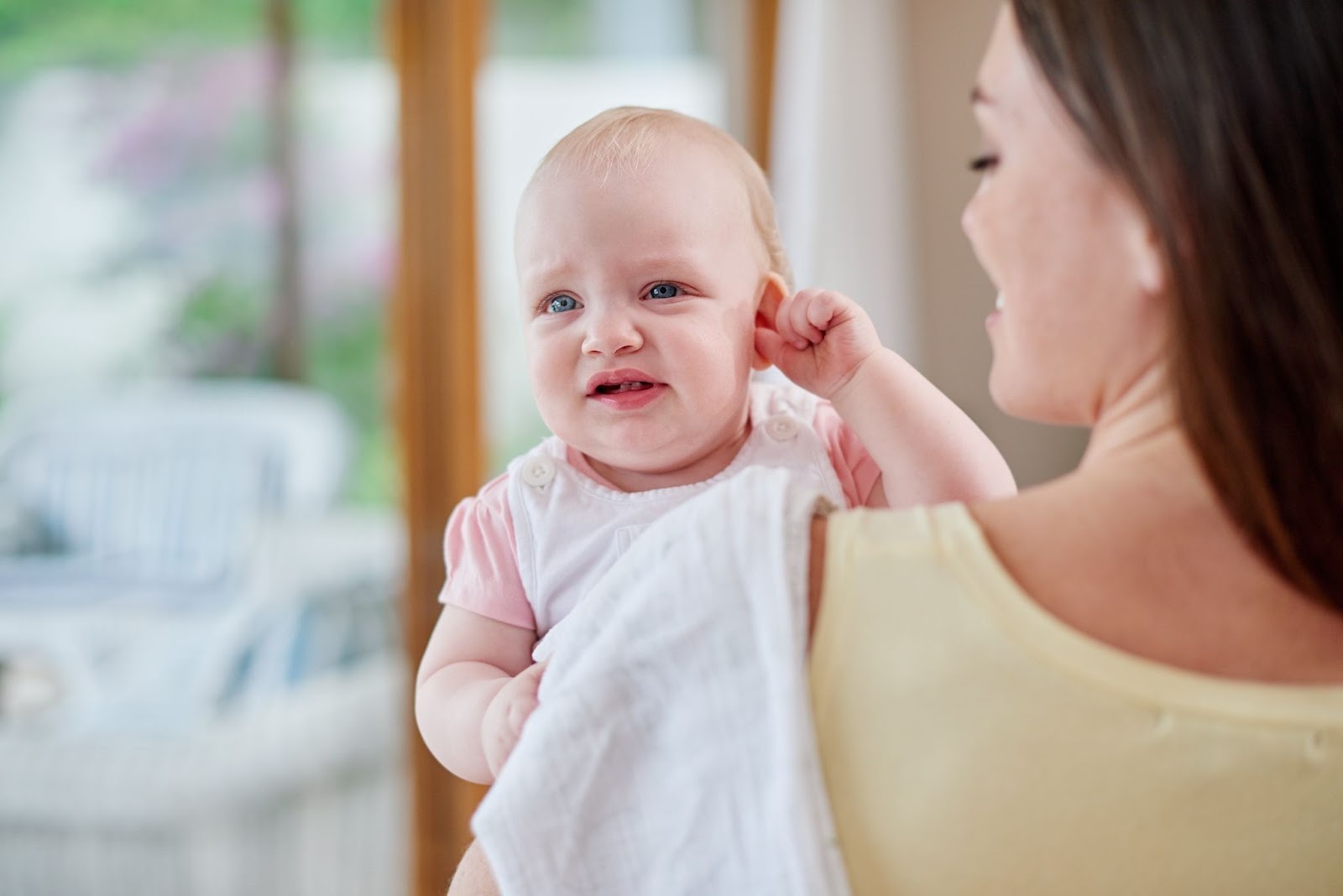 A baby tugging at her ears because of an ear infection
