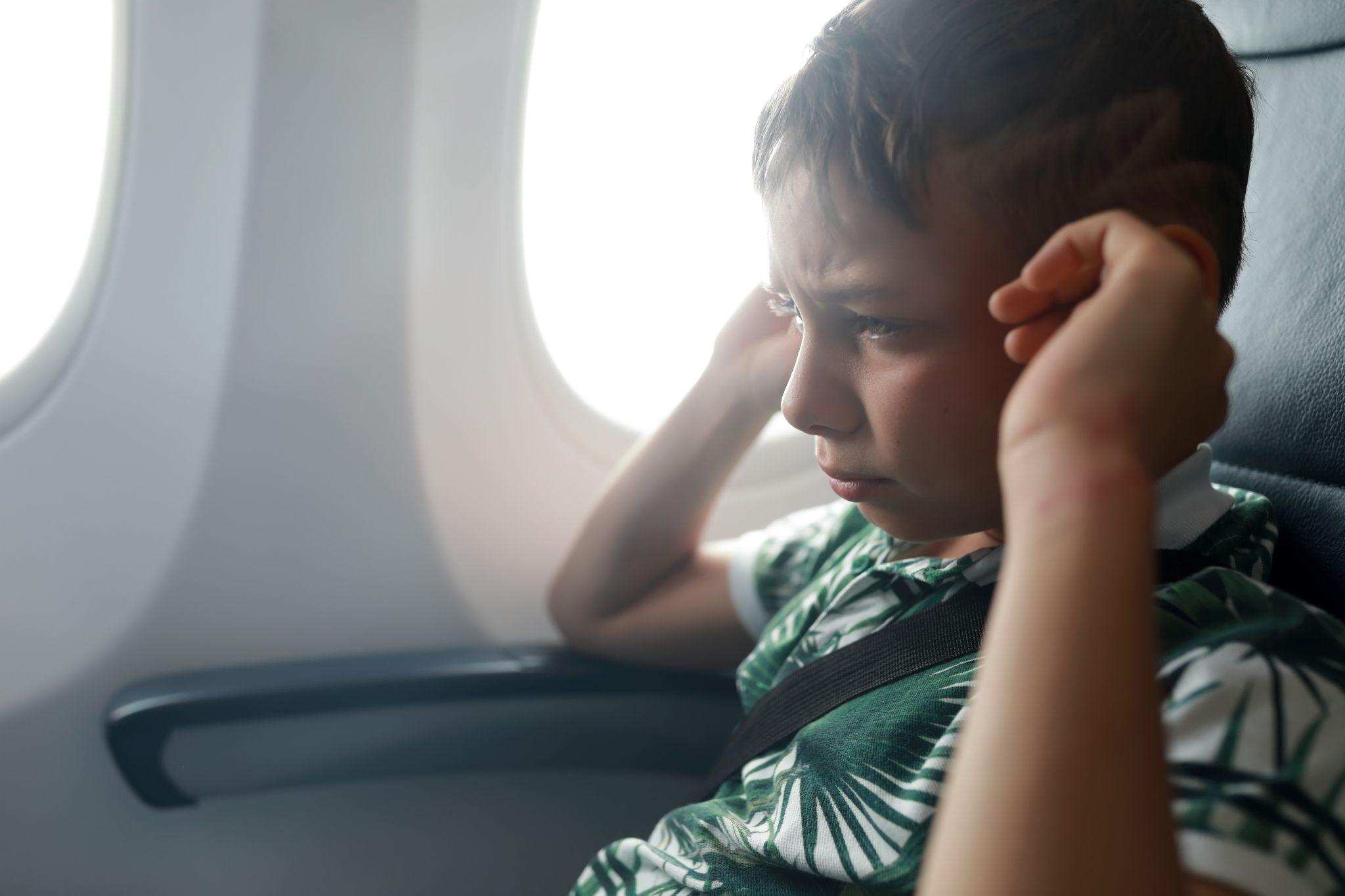 A child holding his ears in pain on an airplane