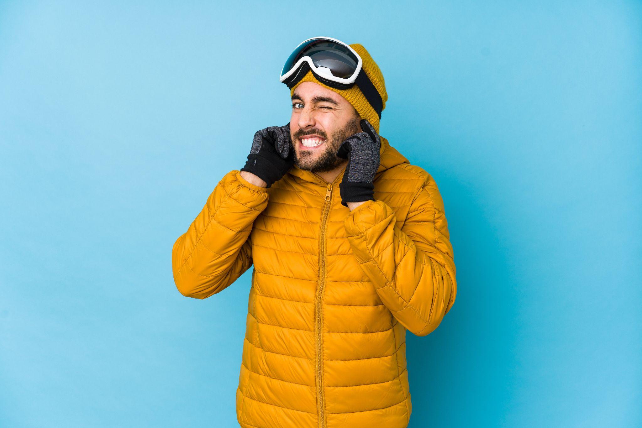 A man in winter gear holding his ears