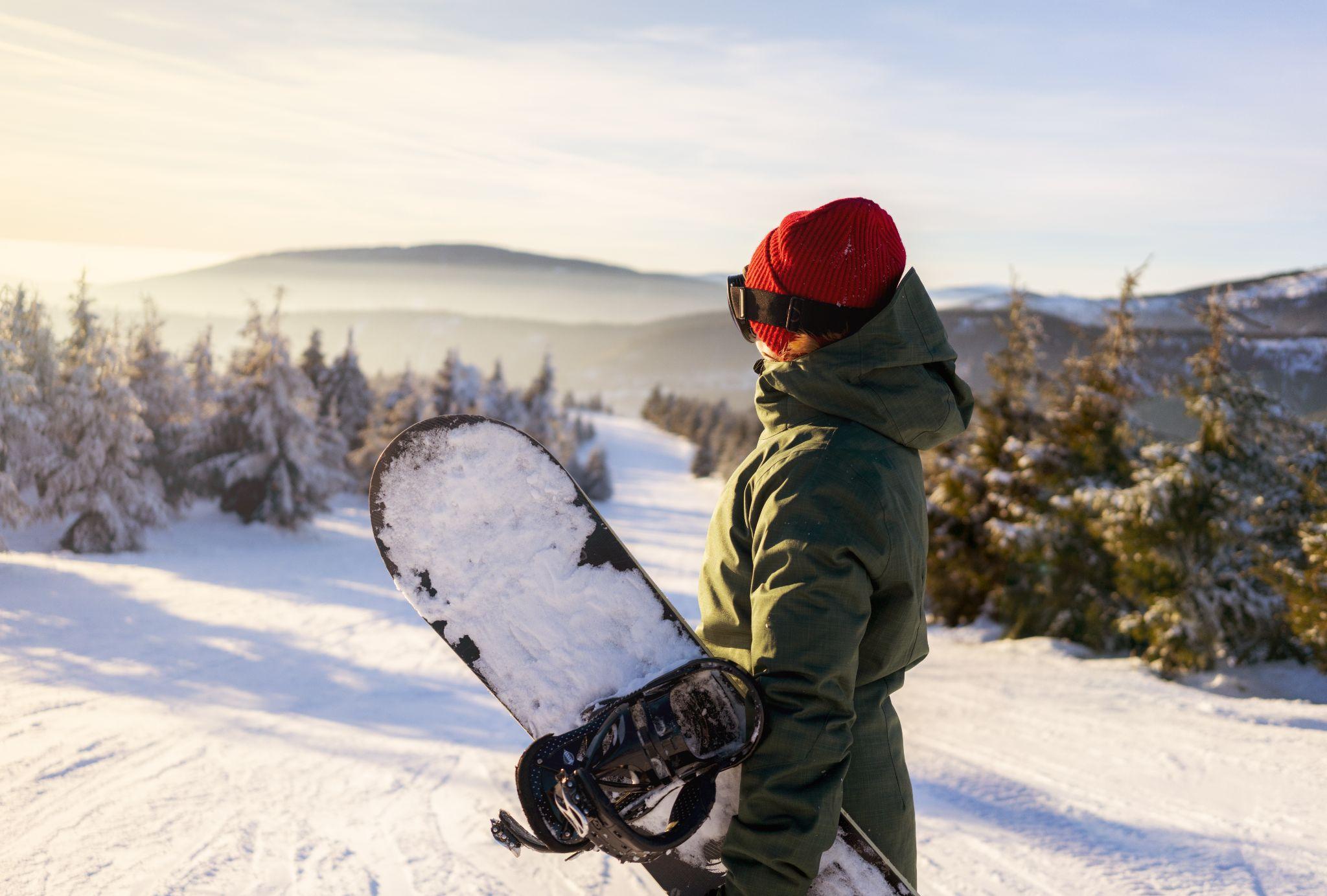 A snowboarder looking out at snowy mountains
